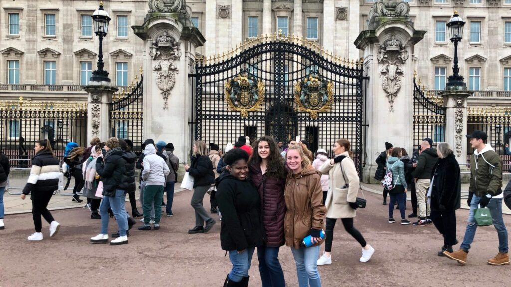 a group of students posing for a picture in front of a gated building