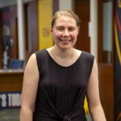 a woman in a black sleeveless dress smiling at camera