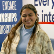 a woman in a blue turtleneck smiling at camera