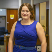 a smiling woman in a sleeveless blue dress