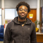 a smiling student wearing glasses and a black jacket