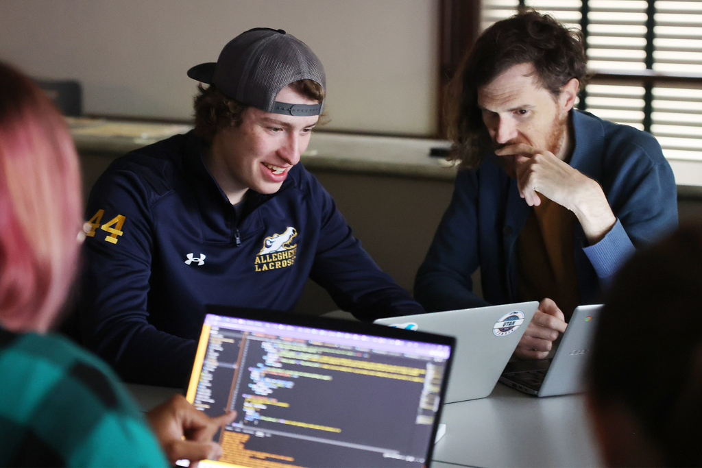 a group of men looking at a laptop screen