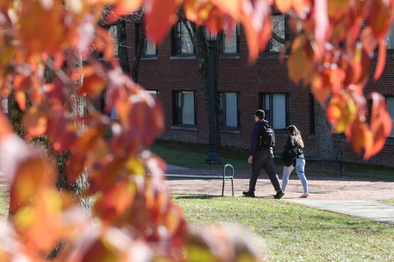 students walking on campus with fall leaves in the foreground