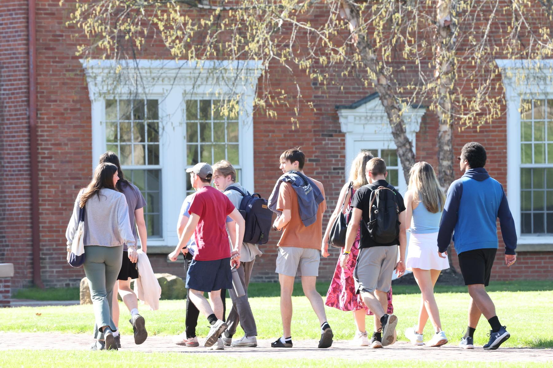 a group of students walking on a sidewalk