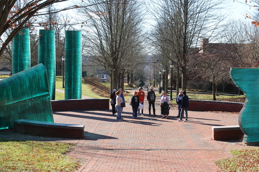green glass sculptures with a group of people standing in the middle of them outside