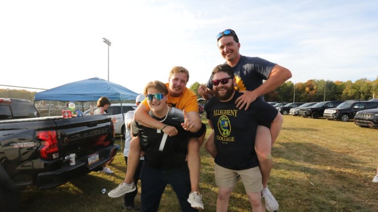Two people pose on the backs of two other people at the Robertson Athletic Complex during the 2025 Blue and Gold Weekend.