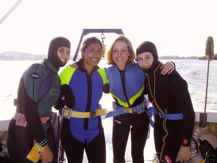 Students in scuba gear stand in a boat