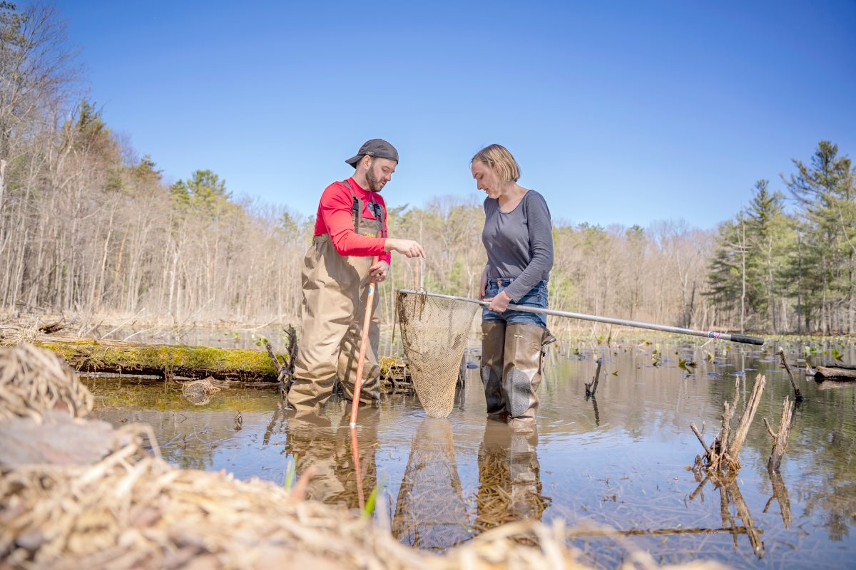 professor and student conduct research in a pond