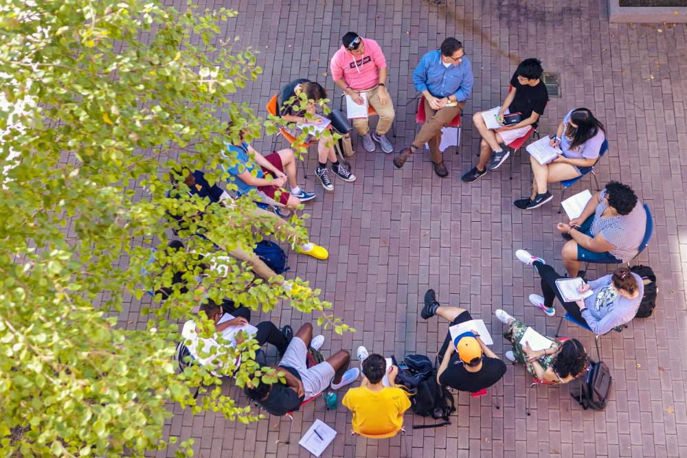 Aerial view of students having class outside in a circle.