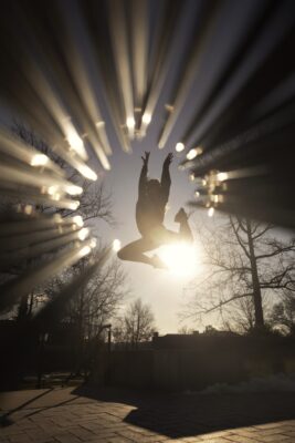 silhouette of a person jumping in the air in front of the sun