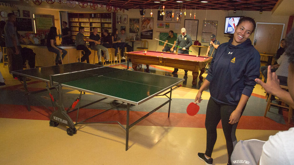 a group of people playing ping pong and pool