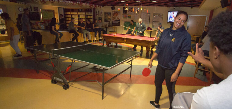 a group of people playing ping pong and pool