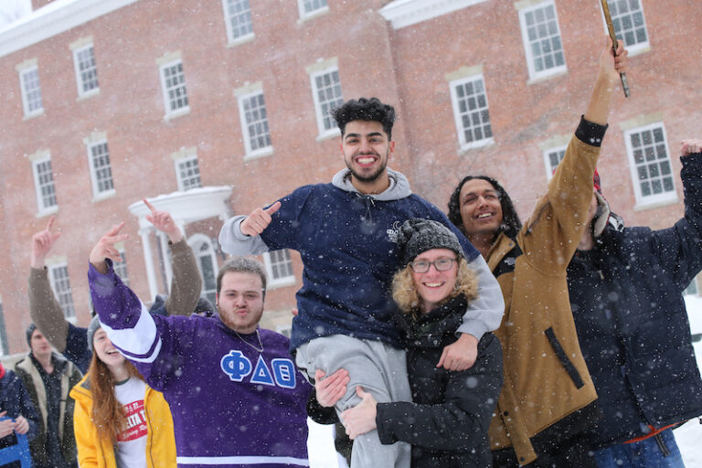 five mail students smiling and holding their arms up