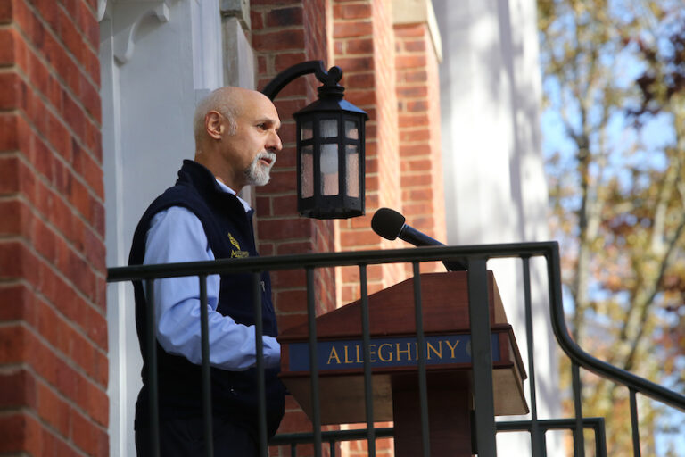 A profile view of President Ron Cole speaking at a podium outdoors