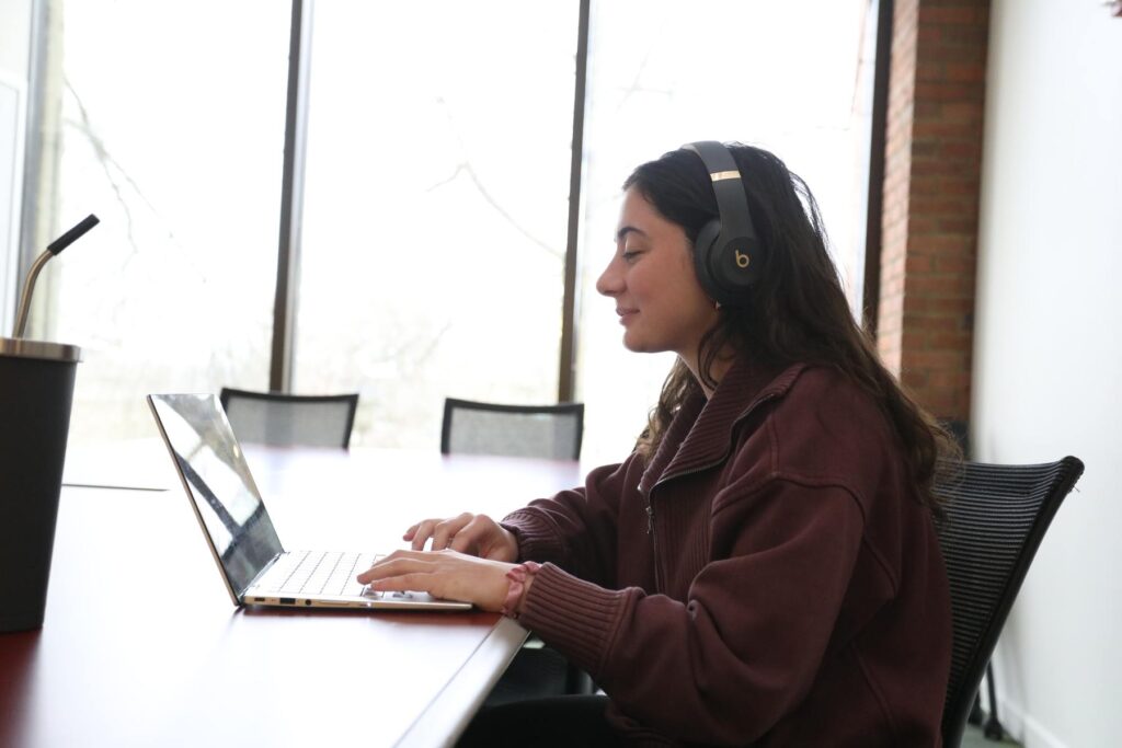 Student wearing headphones and working on a laptop in the library.