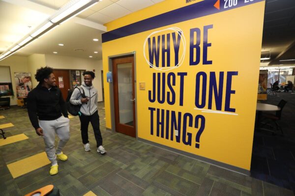 two students walk near a sign reading 