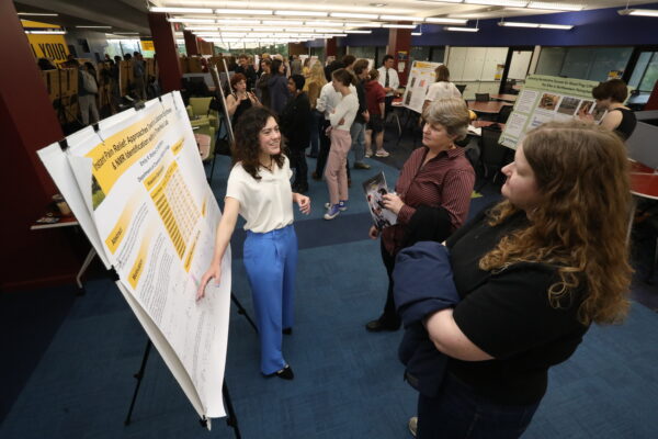 Student presenting their research with their poster