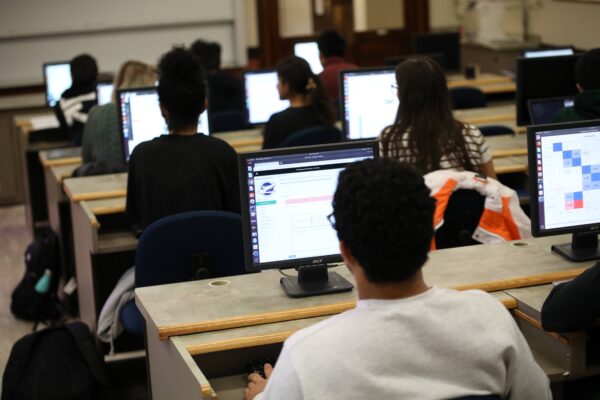 a group of people in a classroom with computer monitors