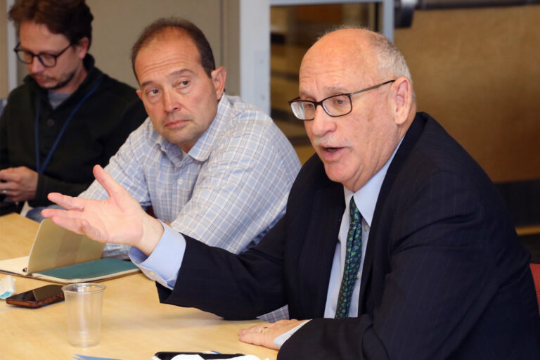 a person in a suit and tie seated at a table talking