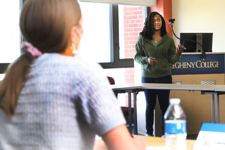 a person standing in front of a student in a classroom