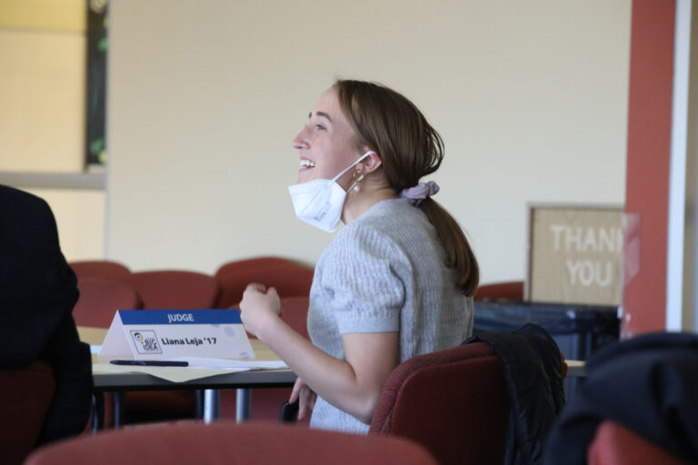 a woman wearing a mask seated at a table laughing