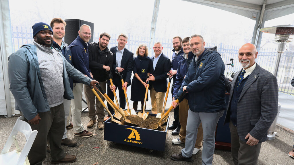 Football coaching staff shoveling dirt for a groundbreaking
