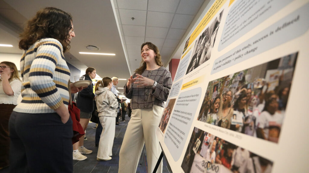Student presenting their poster to a person