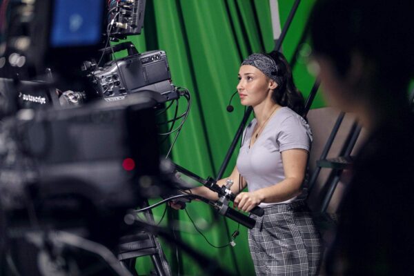 student operating a large video camera in studio