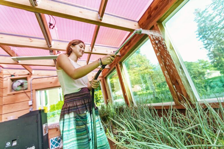 a student watering plants in a greenhouse