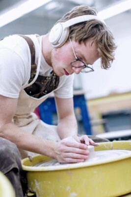 a person wearing headphones working on a pottery wheel