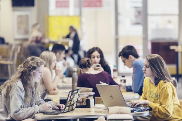 a group of students sitting at tables with laptops