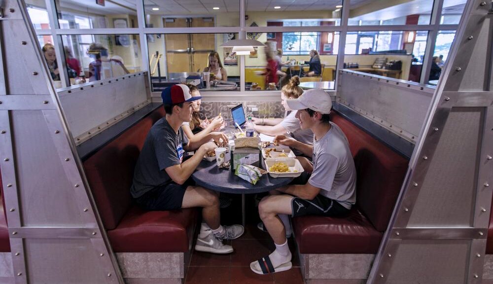 a group of students sitting at a table in a cafeteria