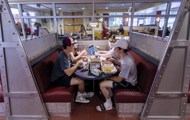 a group of students sitting at a table in a cafeteria