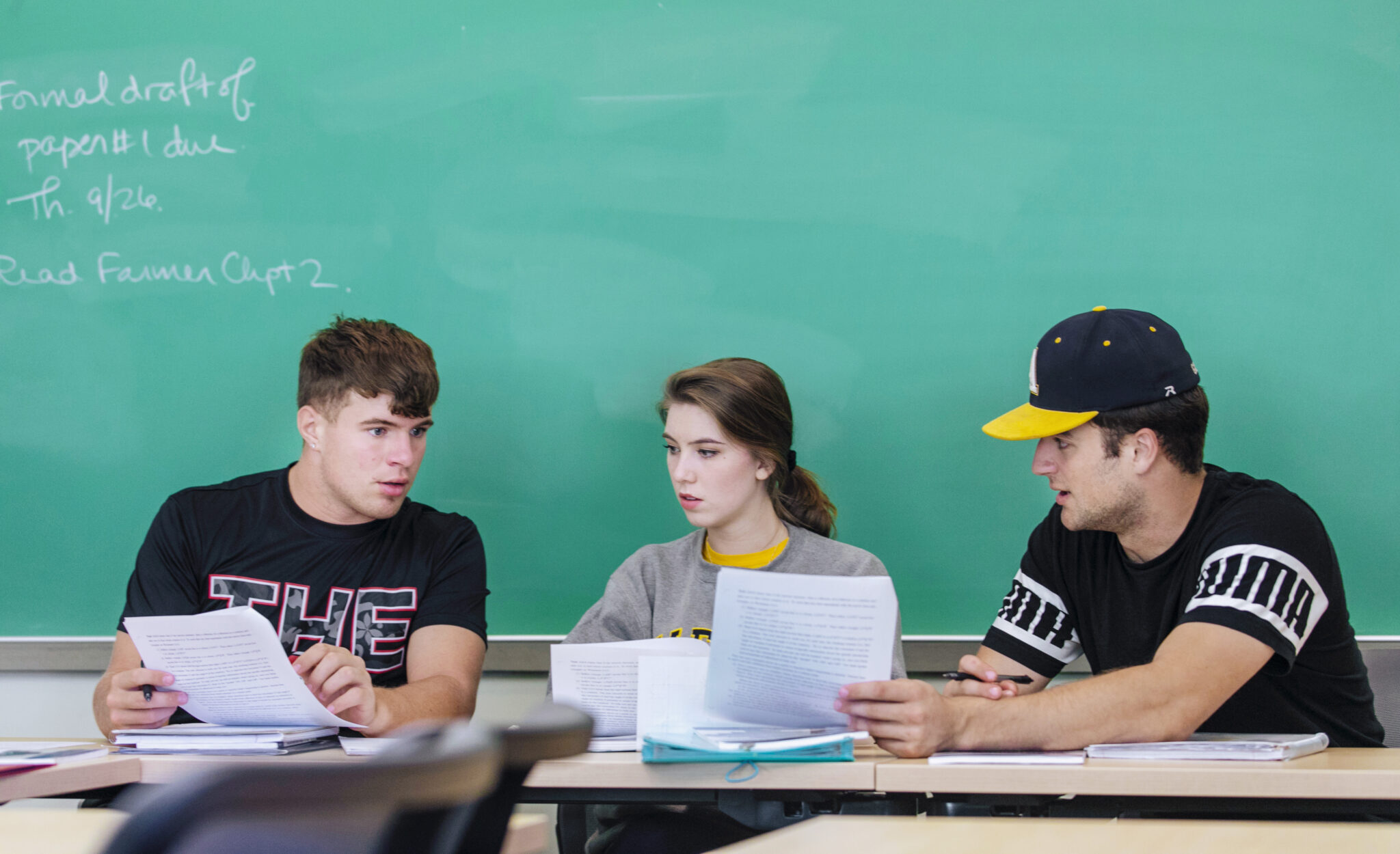 Three students comparing papers