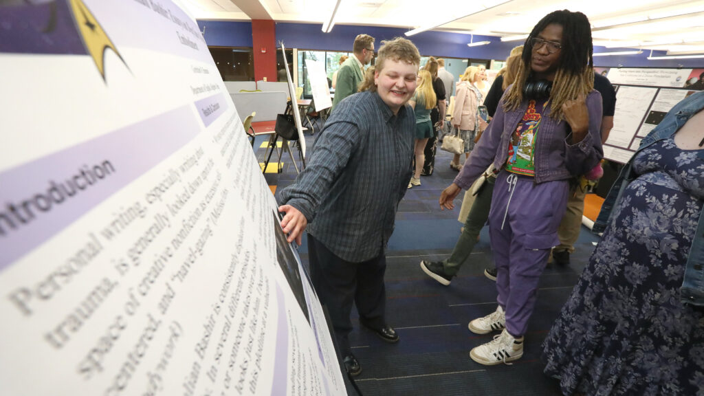 Student pointing to their research presentation