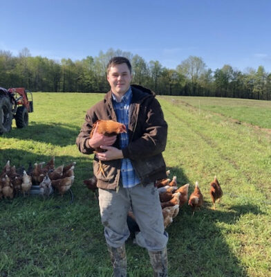 a person holding a chicken in a field