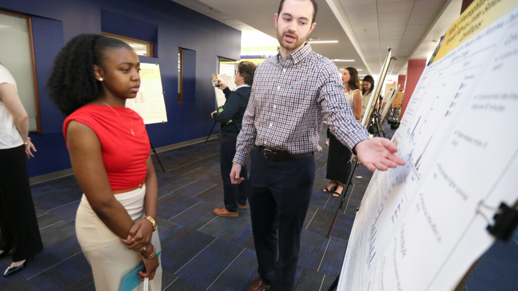 Student speaking to another student about their research poster