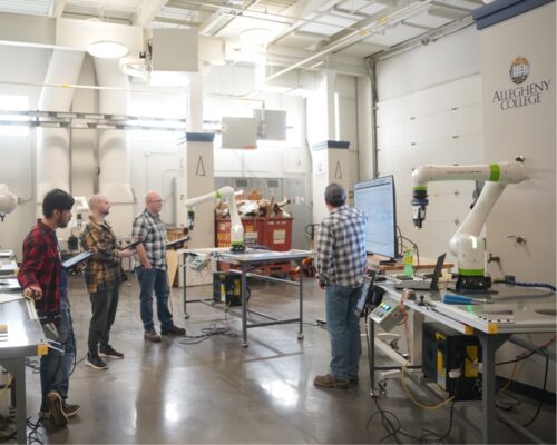 A group of people stand and listen to a presentation at Allegheny College's ALIC @ Bessemer campus