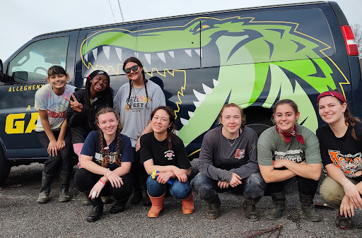 a group of students posing in front of a van with a green alligator painted on its side