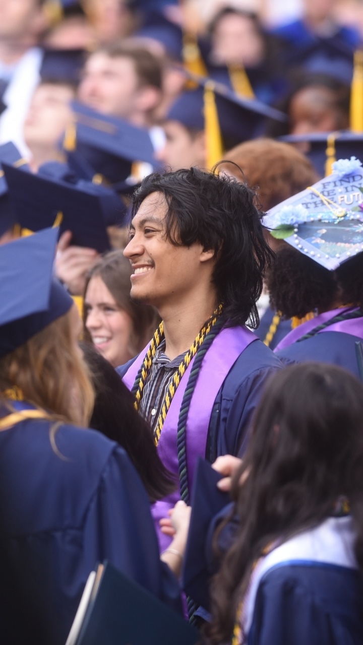 An Allegheny College graduate smiles in the middle of a crowd during Commencement