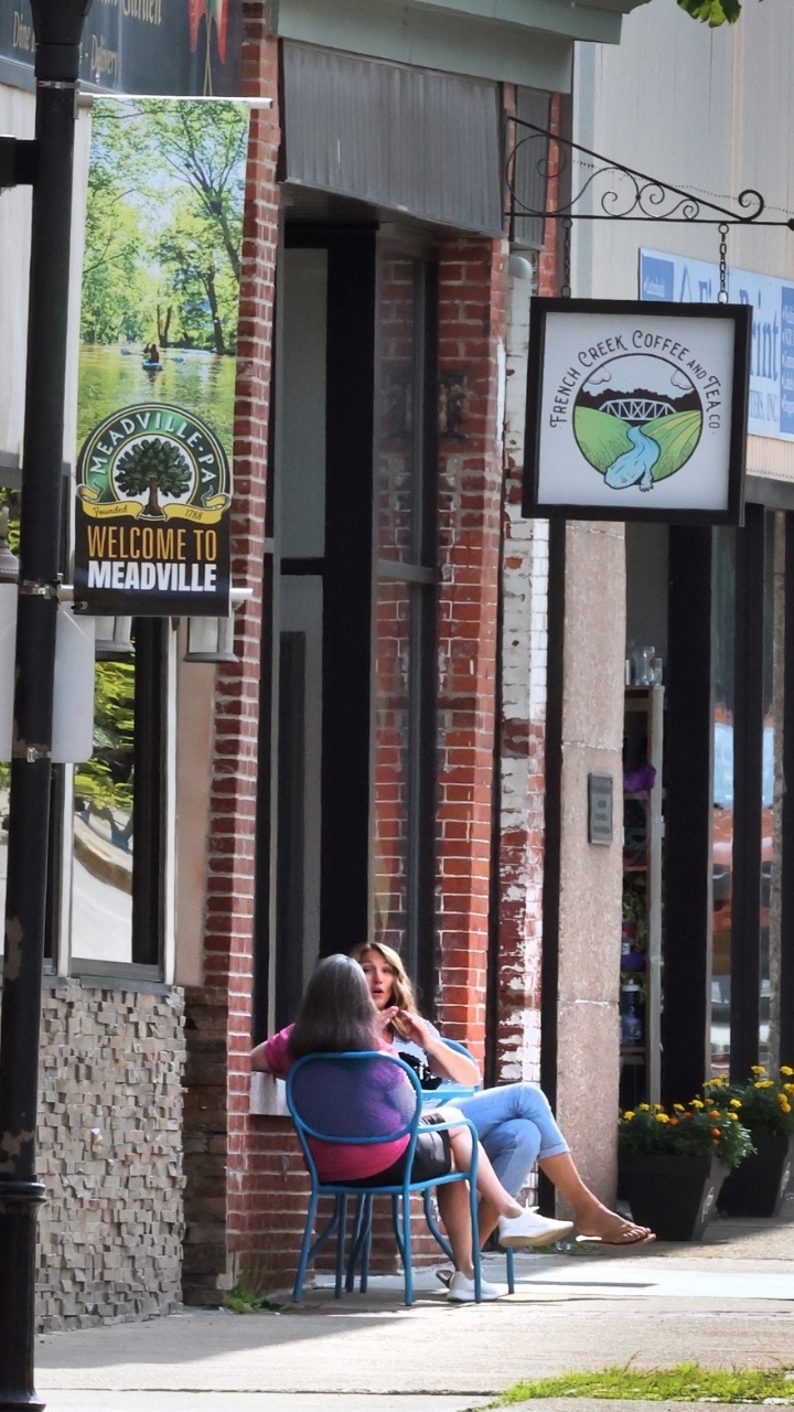 Two people sit at a table outside the French Creek Coffee and Tea shop in Meadville, PA