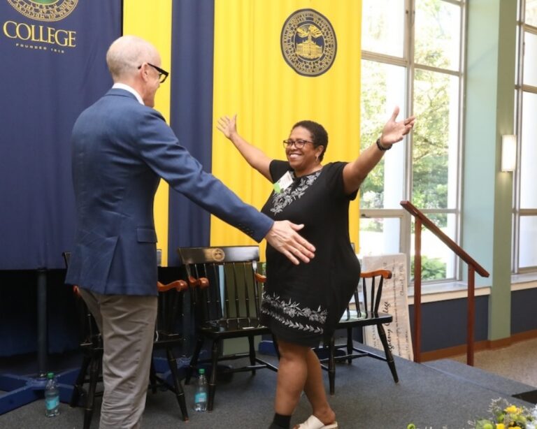 A woman and a man about to hug on a stage at Allegheny College