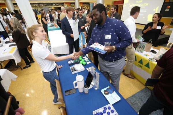 Two people shake hands at a networking event