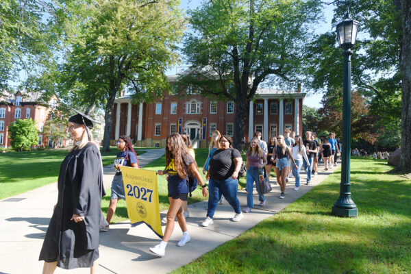 a group of students walking on a sidewalk while holding a yellow banner