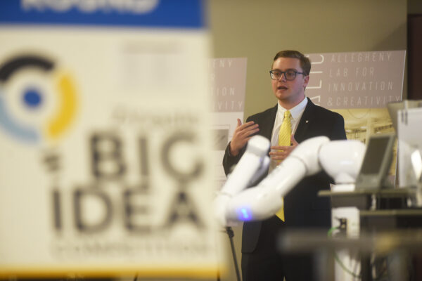 a man in a suit giving a presentation next to a sign that reads big idea