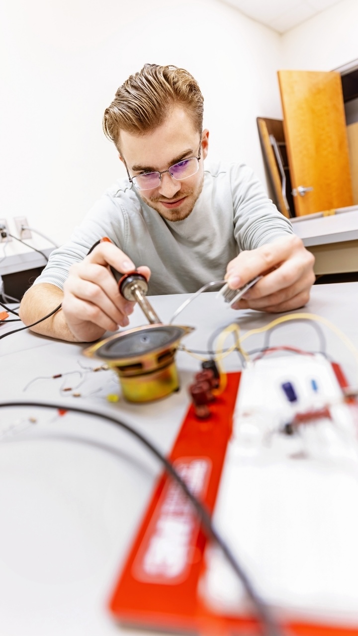 A person sits a table and works on a wiring project