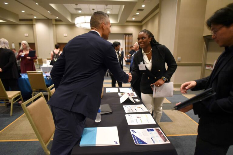 two people leaning over a table and shaking hands