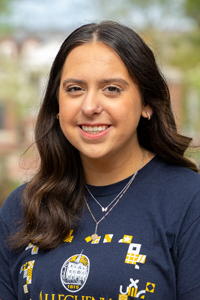 Dark haired woman wearing navy t shirt and necklaces