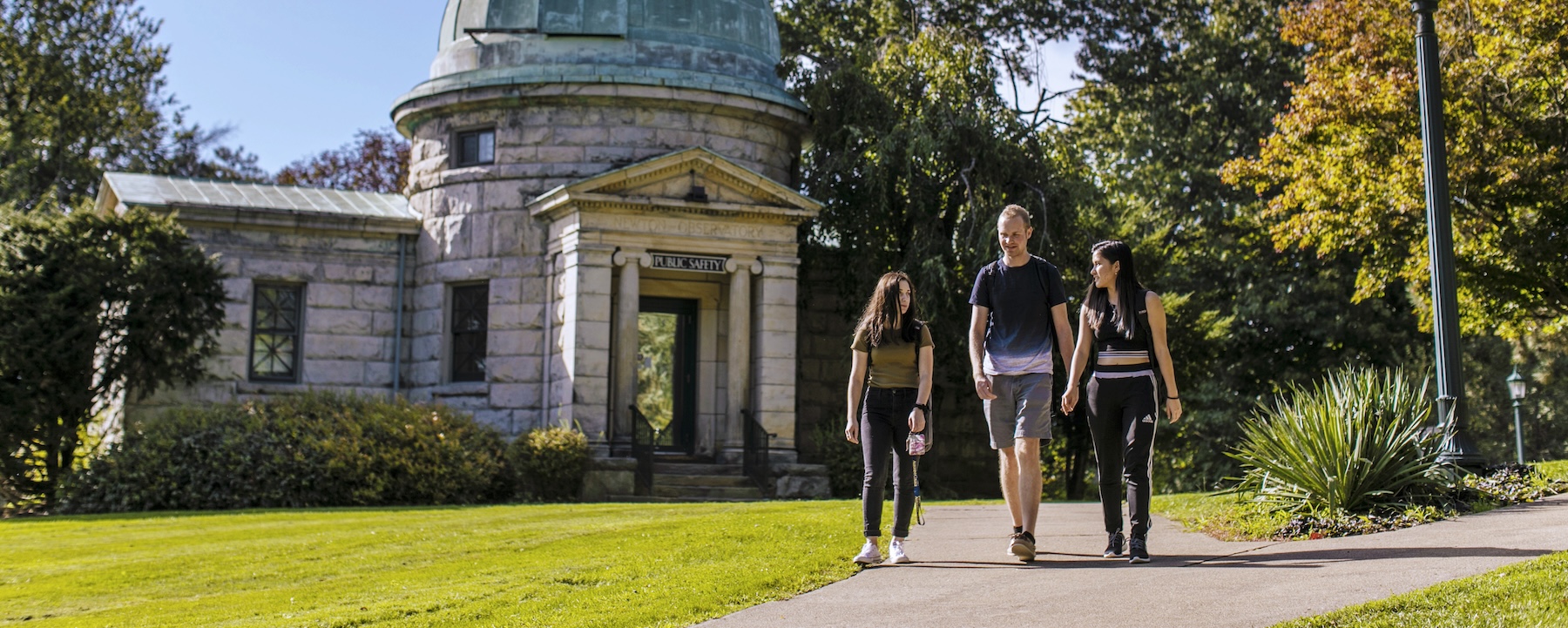 Three people walk in front of the Newton Observatory at Allegheny College