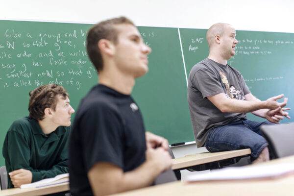 a group of students sitting in a classroom in front of a chalkboard